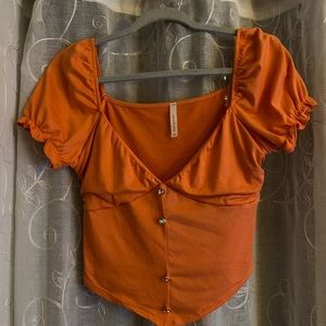 Low V- cut, orange- peach shirt with ruffled sides
